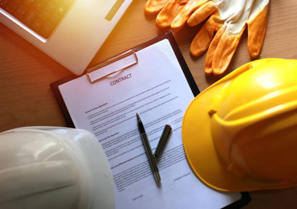 Building hats and gloves resting on a table next to a building work contract