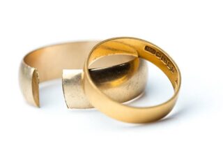 A closeup image of a divorced couple's wedding rings against a white background