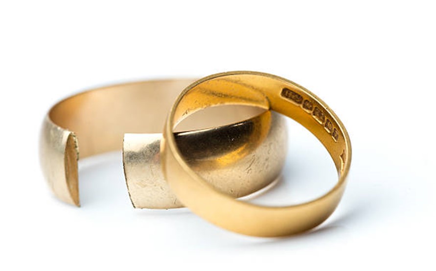 A closeup image of a divorced couple's wedding rings against a white background