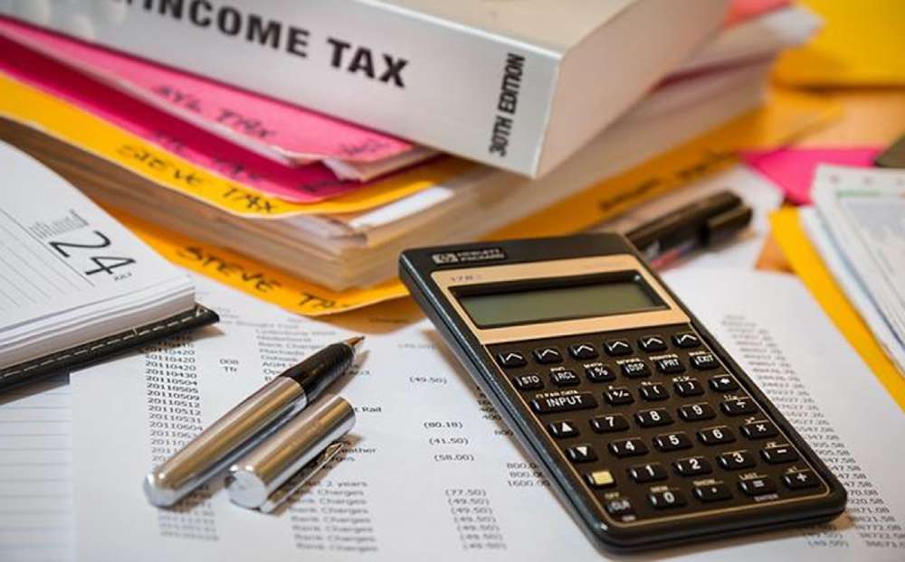 A calculator and pen resting on a file of documents