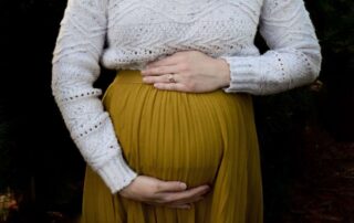 A image of a woman holding her pregnant belly against a black background