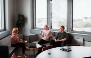 Three employees engage in a meeting in a bright modern office