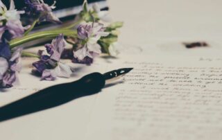 A pen and bouquet of purple flowers resting on a will document