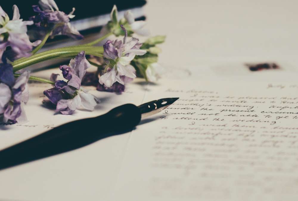 A pen and bouquet of purple flowers resting on a will document