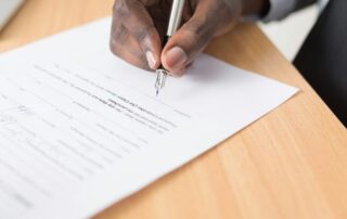 A closeup image of businessman signing a settlement offer