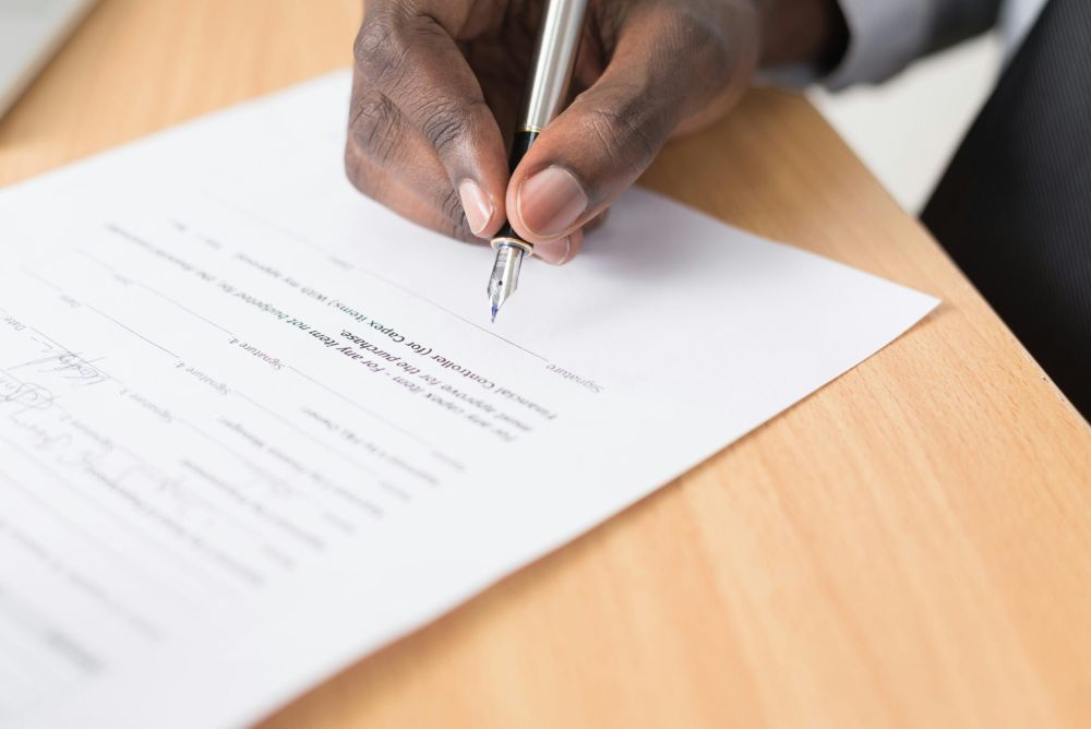 A closeup image of businessman signing a settlement offer