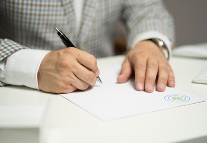 A closeup image of a man signing his will at a desk