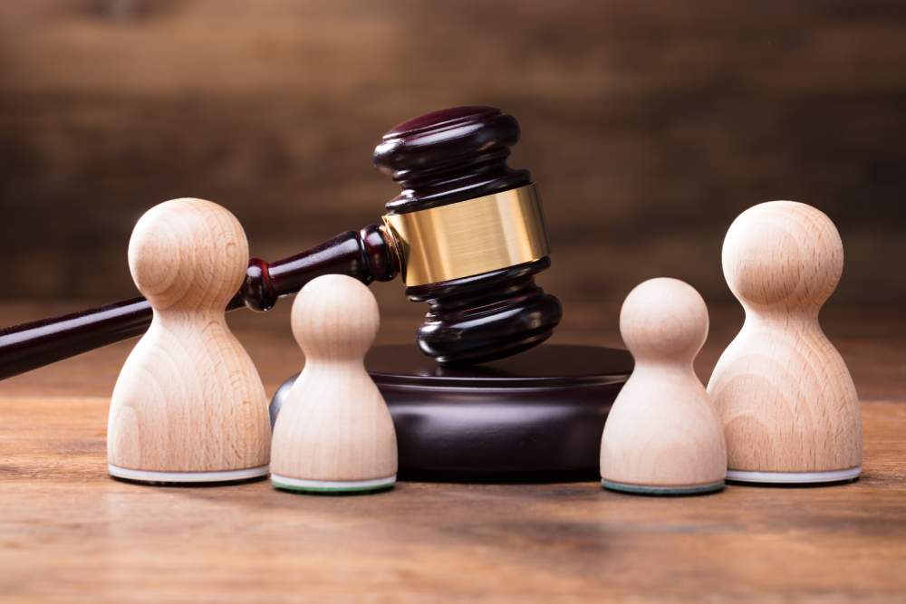 four different sized wooden pawns, representing a family, with a court gavel in the middle