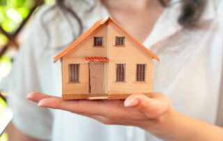 a woman holding a small wooden house in her hand