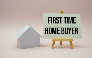 a small white house next to a sign that says first time home buyer