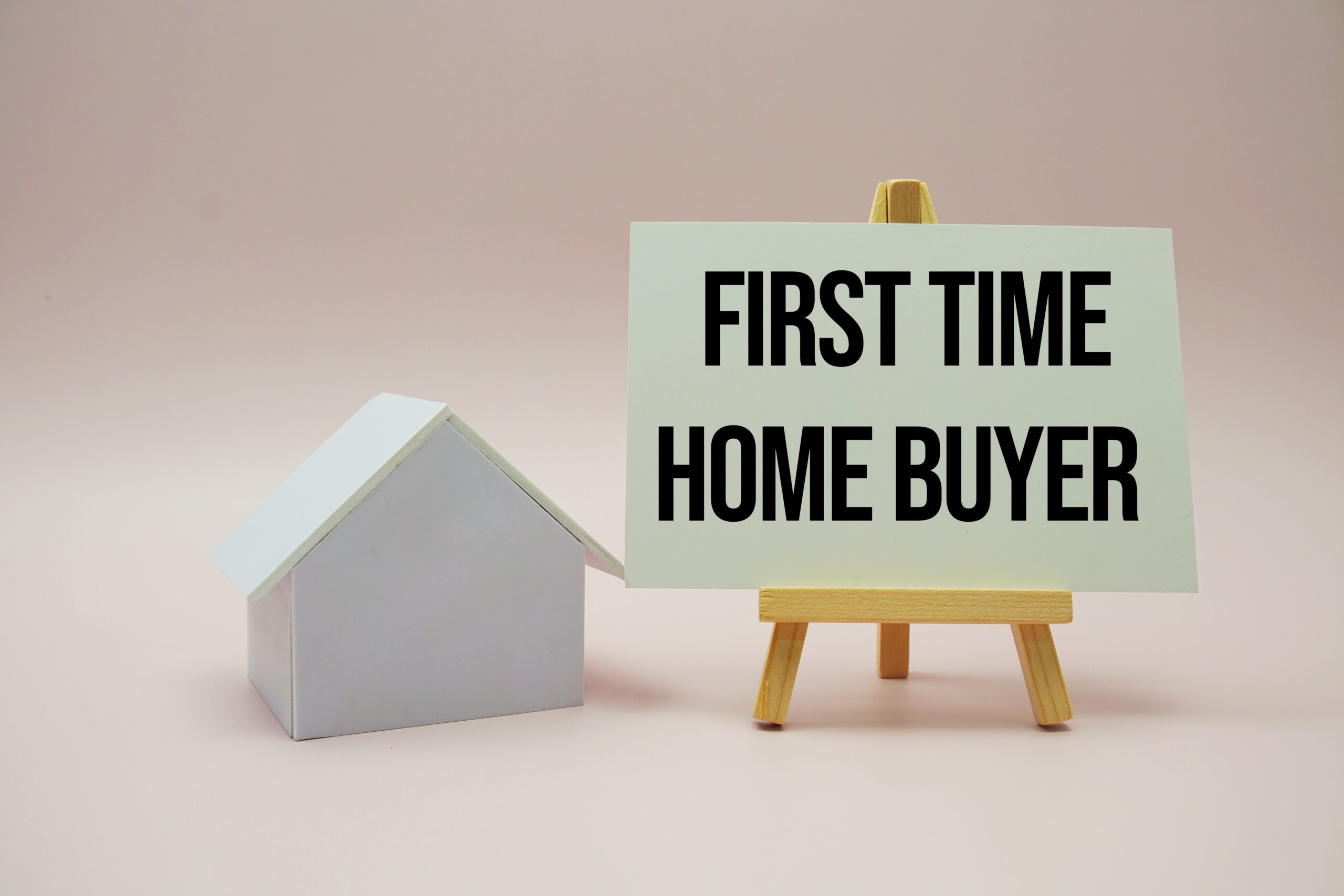 a small white house next to a sign that says first time home buyer