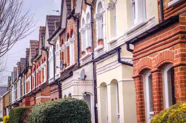 A row of traditional British red brick terraced houses, pictured on a cloudy day