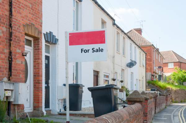 A "for sale" sign displayed on the front of a terraced house