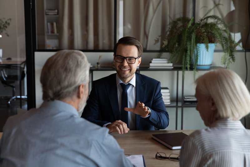 A smiling solicitor gives legal advice to an elderly couple during a consultation.