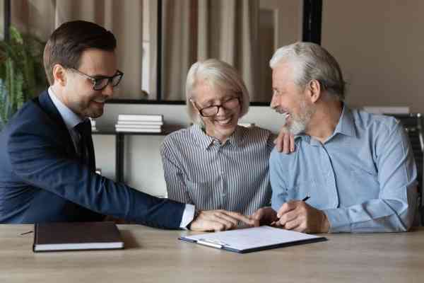 An elderly couple receive legal advice from a cheerful solicitor during a Wills and Trusts consultation