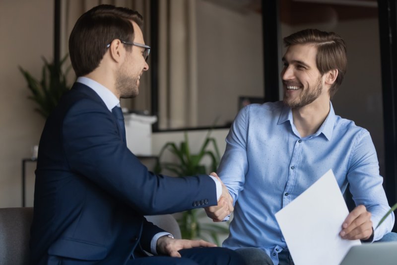 A cheerful client and solicitor shake hands after resolving a will dispute