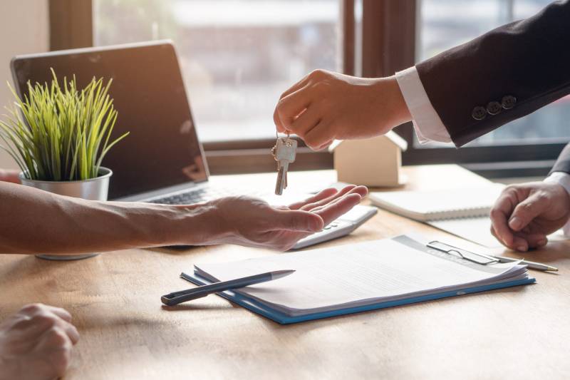 A lettings agent passes a set of house keys to a tenant