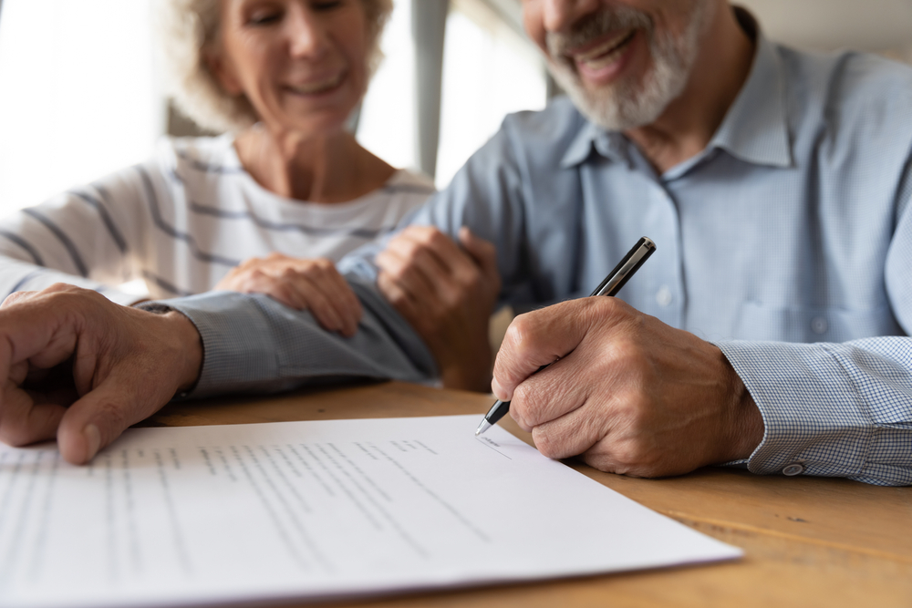 Smiling old couple put signature on document