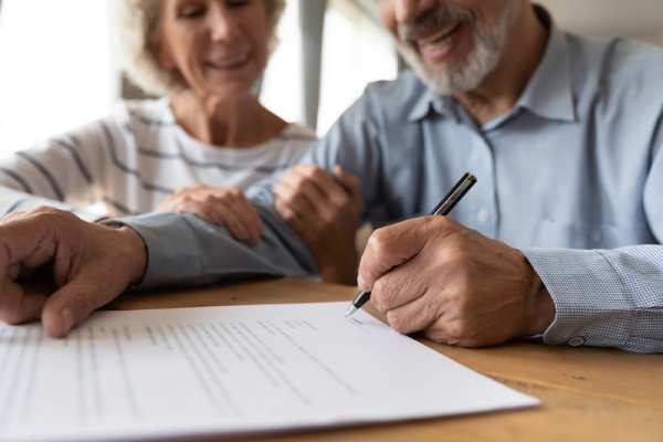 Family Law Fees A smiling old couple put a signature on document during a family law consultation