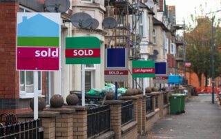 A row of English terraced houses with signs saying "sold" posted outside